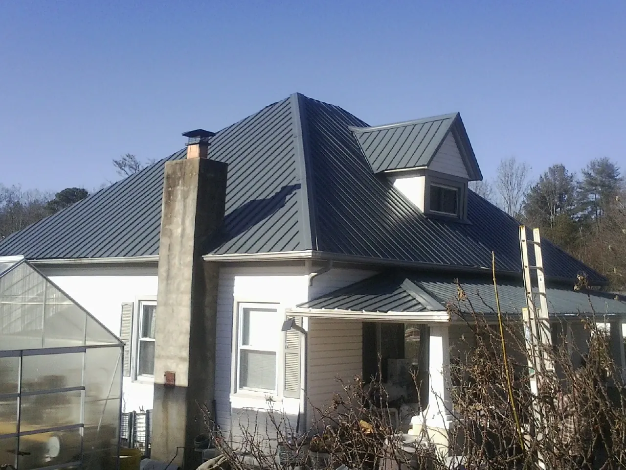 Dark blue standing seam metal roof on a white farmhouse with dormer — Slate & Tile Roof Repair by Roofing Brothers in Tangent