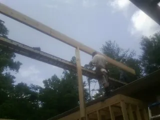 Carpenter setting a ridge beam over a new addition frame — Ice Dam Removal by Roofing Brothers in Tangent