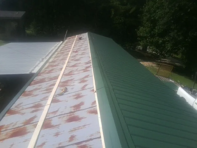 Old rusted panels beside newly installed green metal roofing — Wind Damage Roof Repair by Roofing Brothers in Tangent