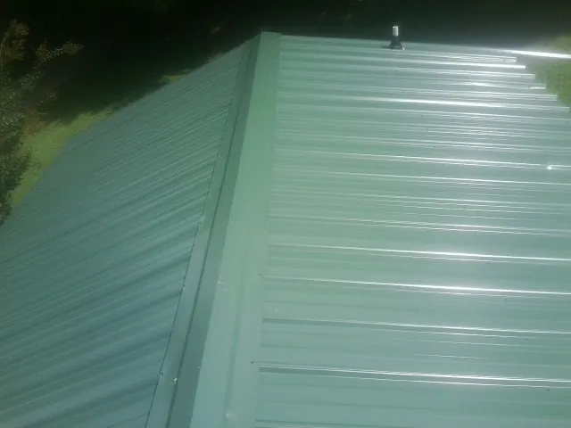 New green metal panels meeting at the ridge of a roof — Flat Roof Repair work by our crew in Tangent