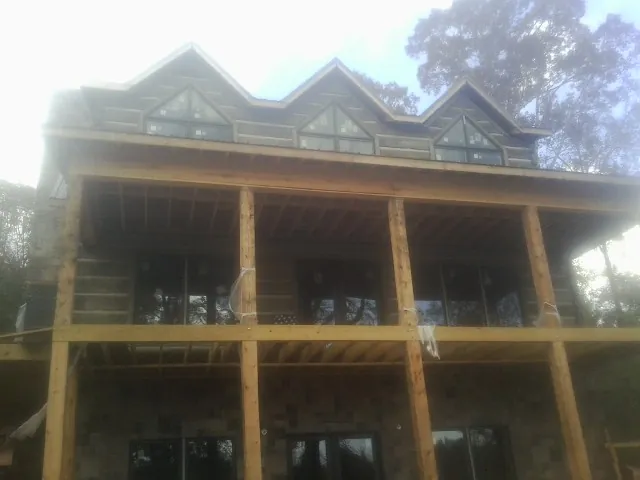 Dormers and porch framing on a large log home under construction — Roof Coating work by our crew in Tangent