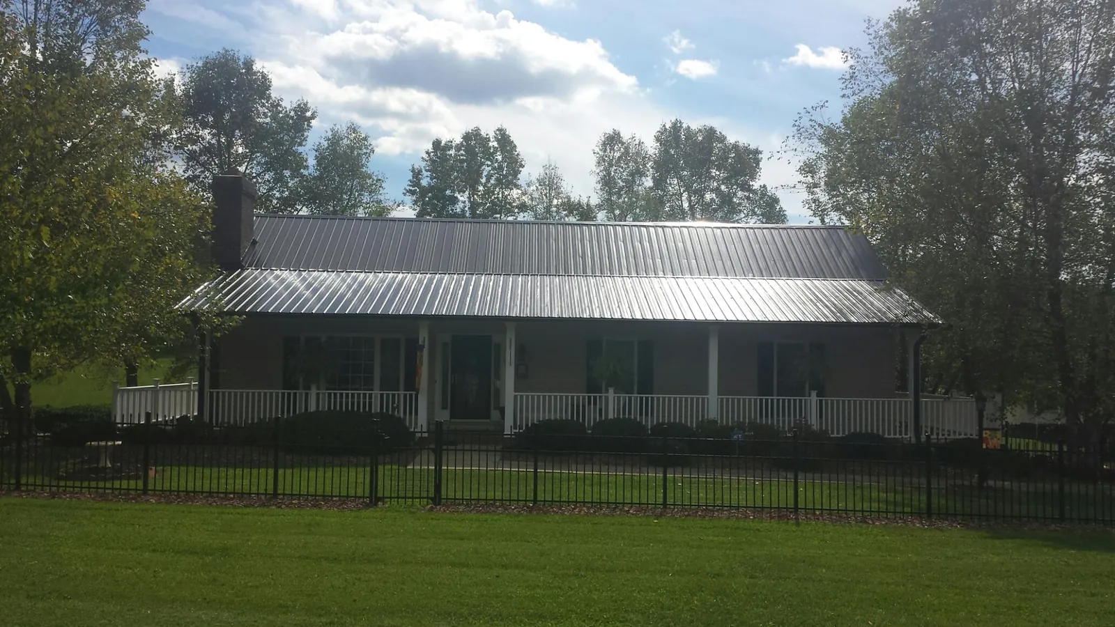 Gray metal roof on a brick ranch with a full width front porch — Gutter Guard Installation work by our crew in Tangent