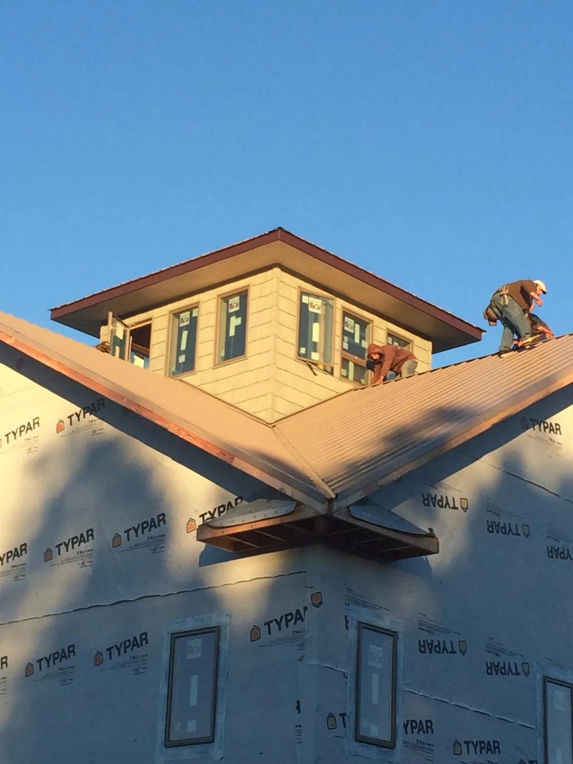 Roofers working around a rooftop cupola on a new metal roof at sunset — Roof Waterproofing in Tangent by Roofing Brothers